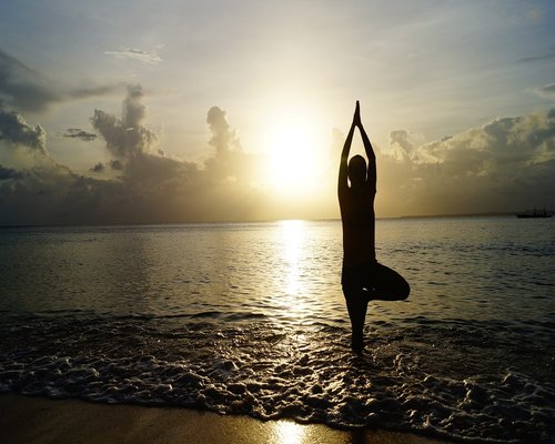 Person practicing meditation yoga outdoors at sunset